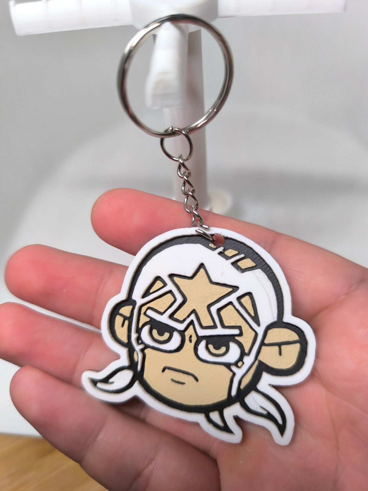 Porte-clés en plastique représentant un visage de dessin animé avec lunettes et étoile sur le front