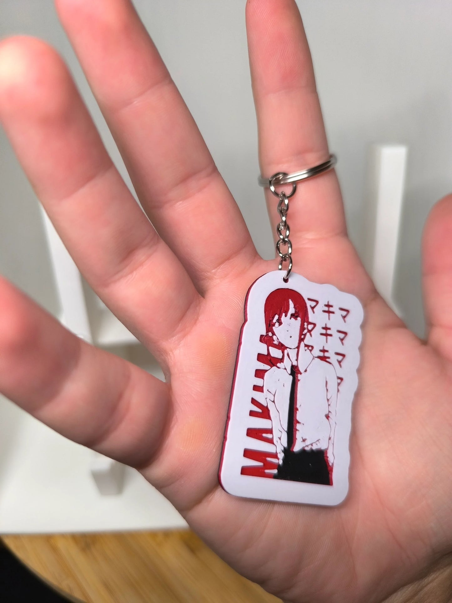 Porte-clés manga avec personnage féminin aux cheveux rouges et chemise blanche tenu dans une main