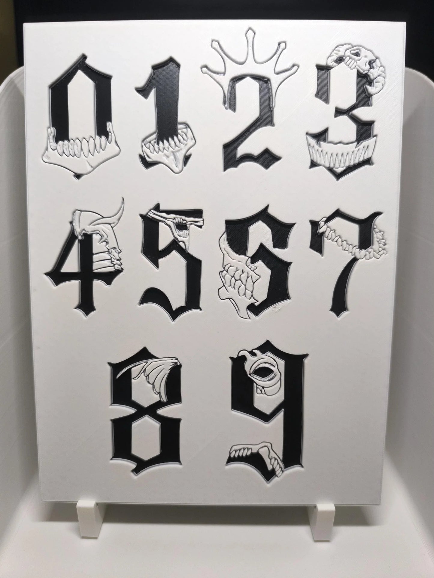Chiffres gothiques noirs de 0 à 9 avec motifs de crânes et dents blancs en relief