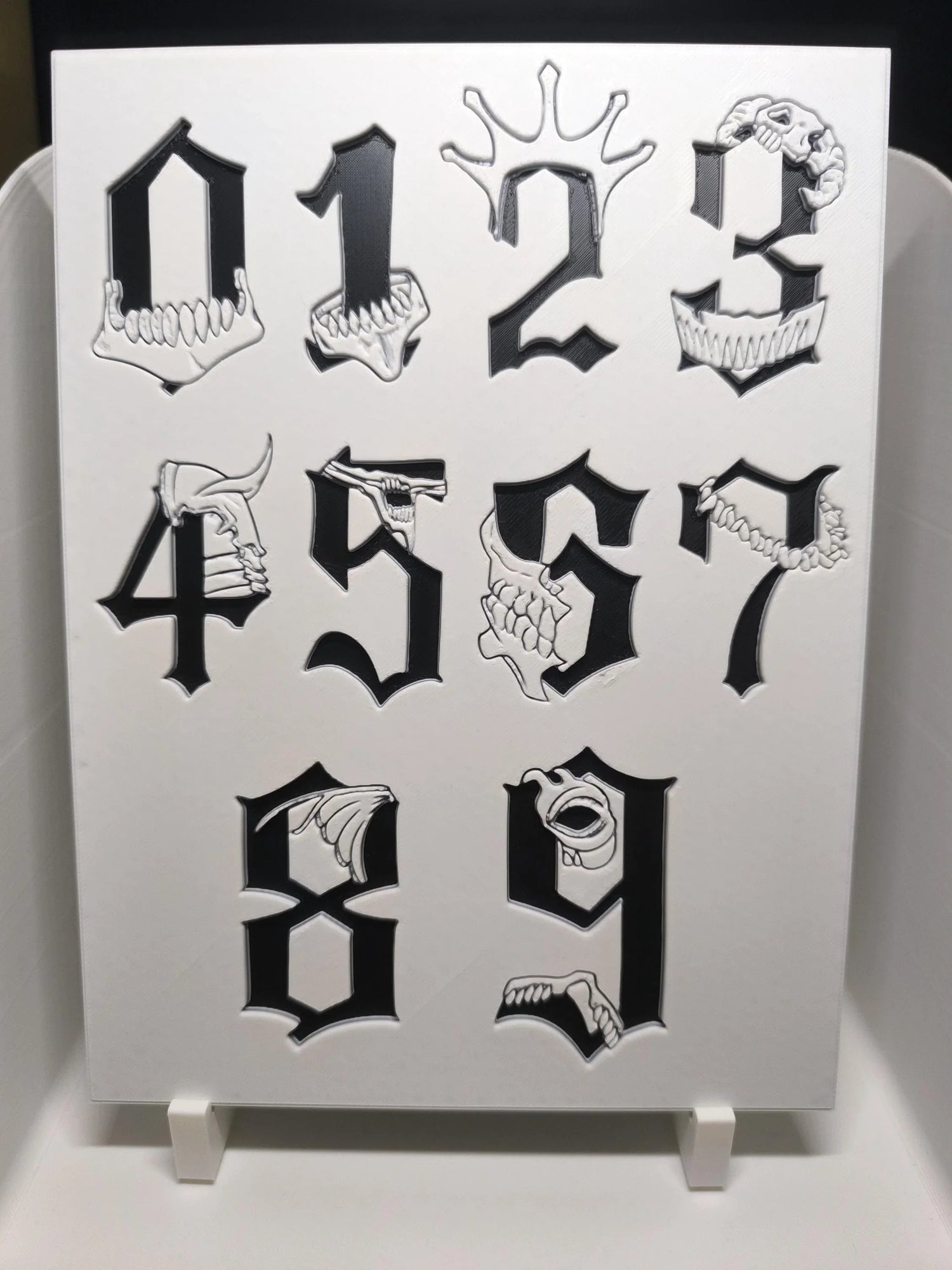 Chiffres gothiques noirs de 0 à 9 avec motifs de crânes et dents blancs en relief