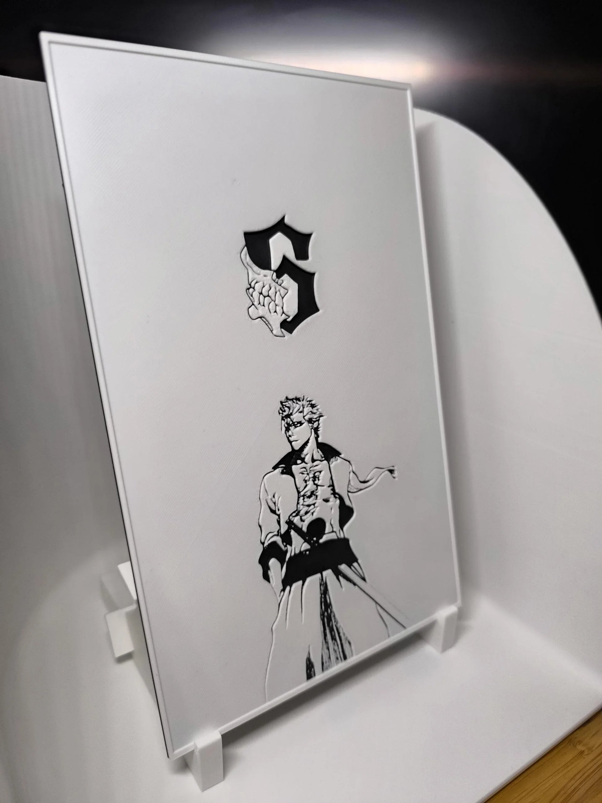 Panneau blanc avec illustration en noir d'un personnage manga stylisé et lettre S gothique