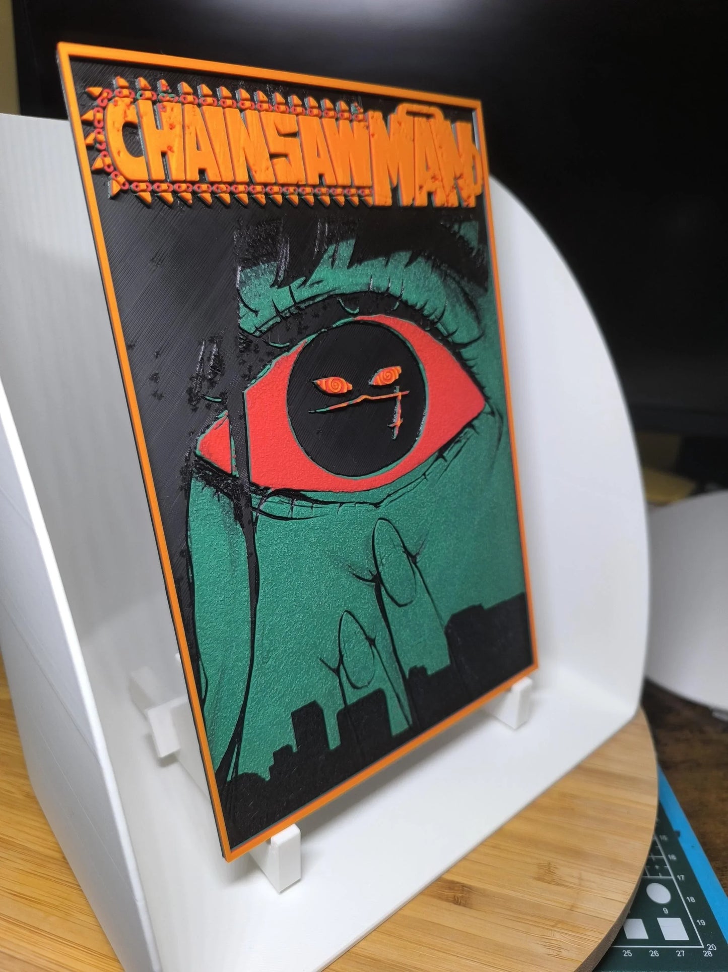 Illustration Chainsaw Man avec gros œil rouge et vert, encadrée sur support blanc