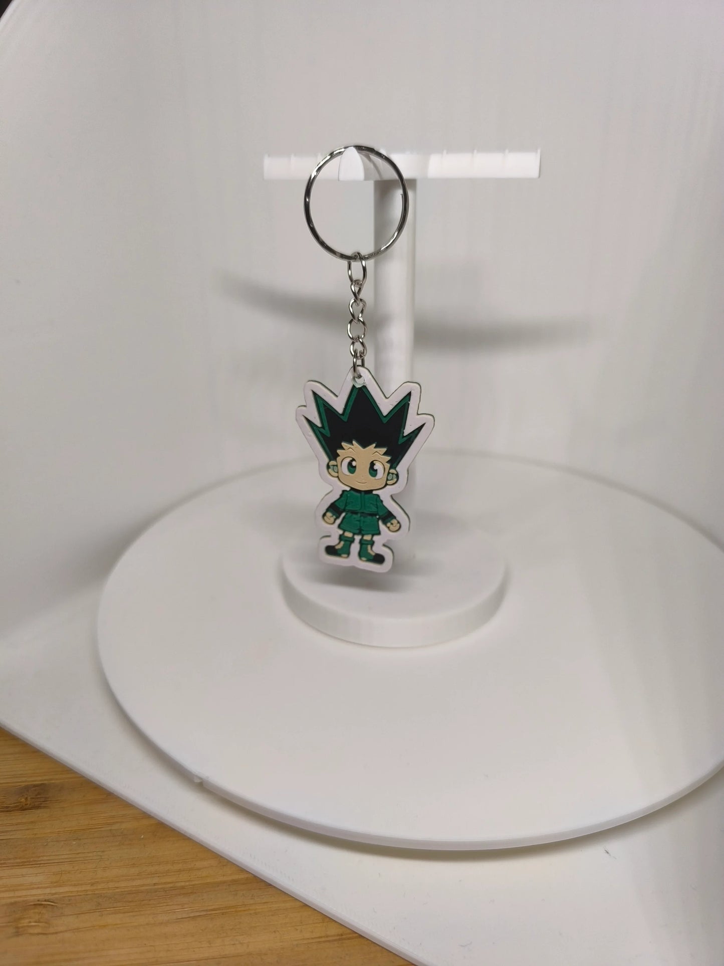 Porte-clés figurine chibi avec cheveux noirs pointus et tenue verte sur support blanc