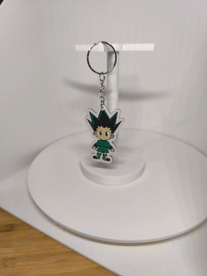 Porte-clés figurine chibi avec cheveux noirs pointus et tenue verte sur support blanc