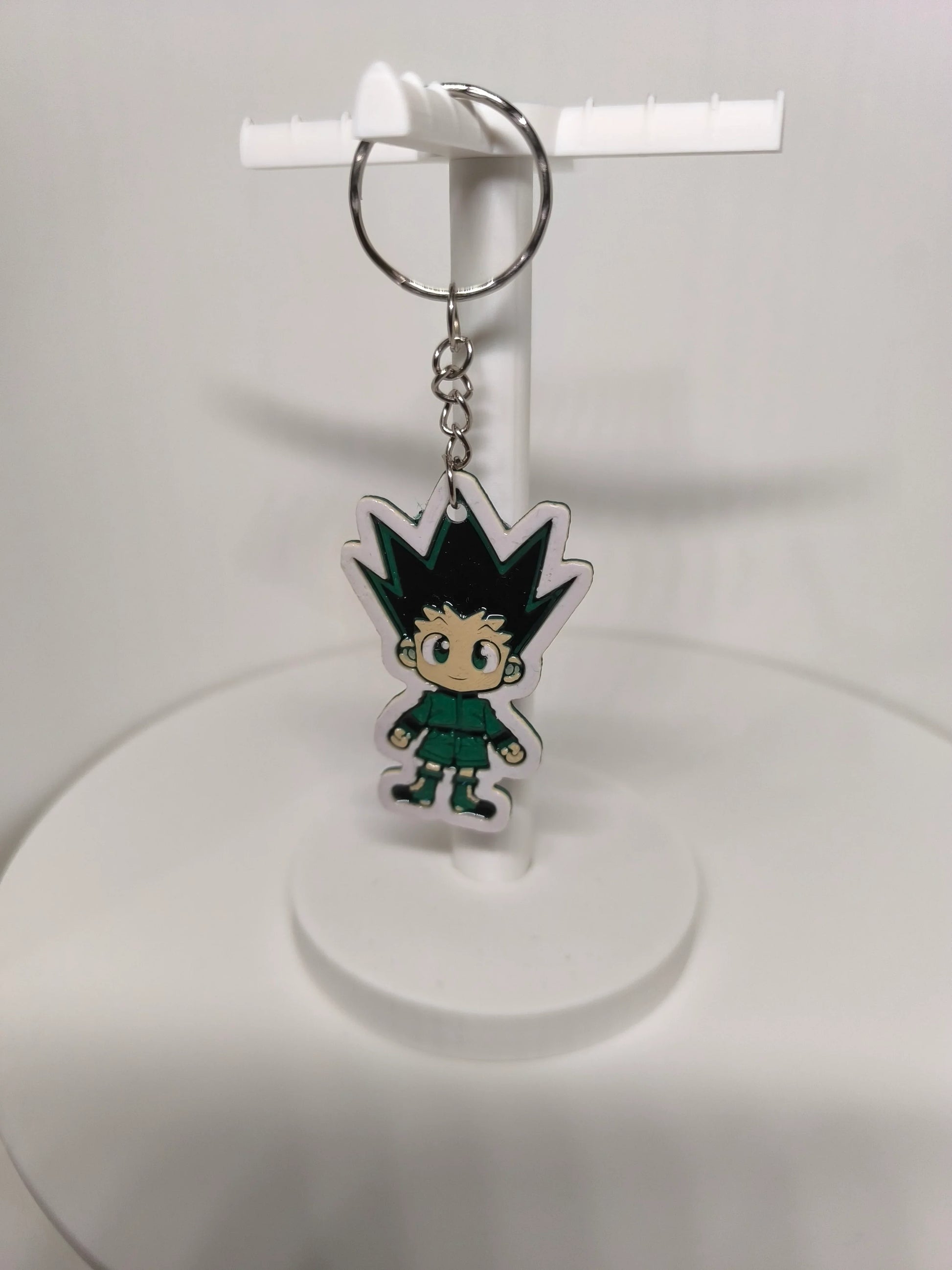 Porte-clés en plastique avec personnage de dessin animé aux cheveux pointus noirs et vert sur support blanc