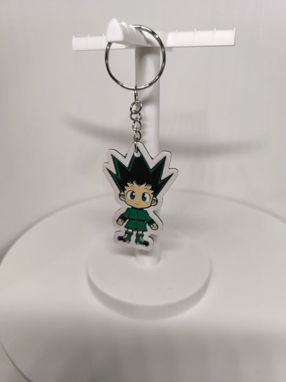 Porte-clés en plastique avec personnage de dessin animé aux cheveux pointus noirs et vert sur support blanc