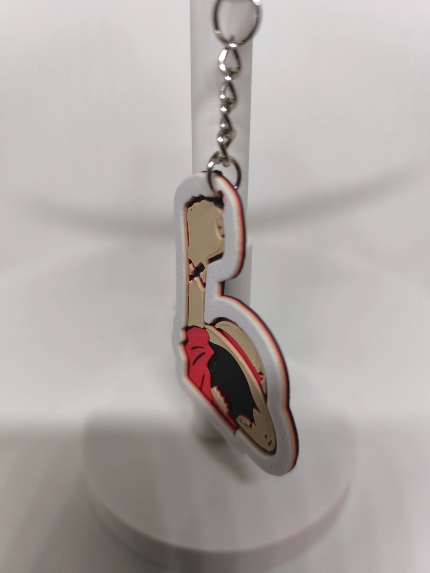 Porte-clés en plastique avec illustration d'une femme en robe rouge, fond blanc flou