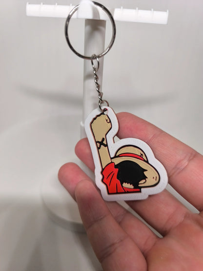 Porte-clés en PVC représentant personnage avec chapeau de paille et bras levé, tenu à la main