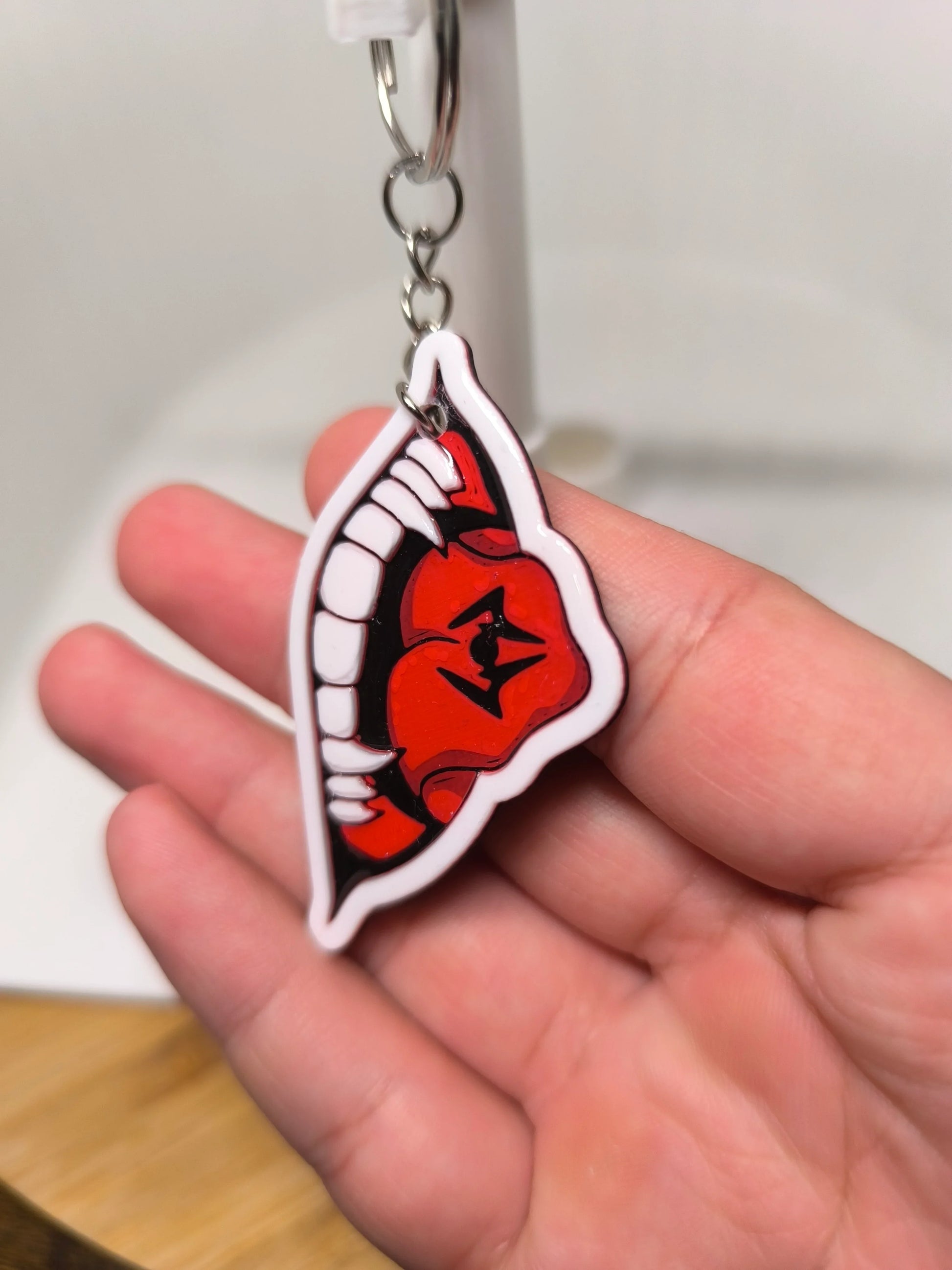 Porte-clés main tenant un porte-clés décoré d'une bouche rouge avec dents blanches et symboles noirs