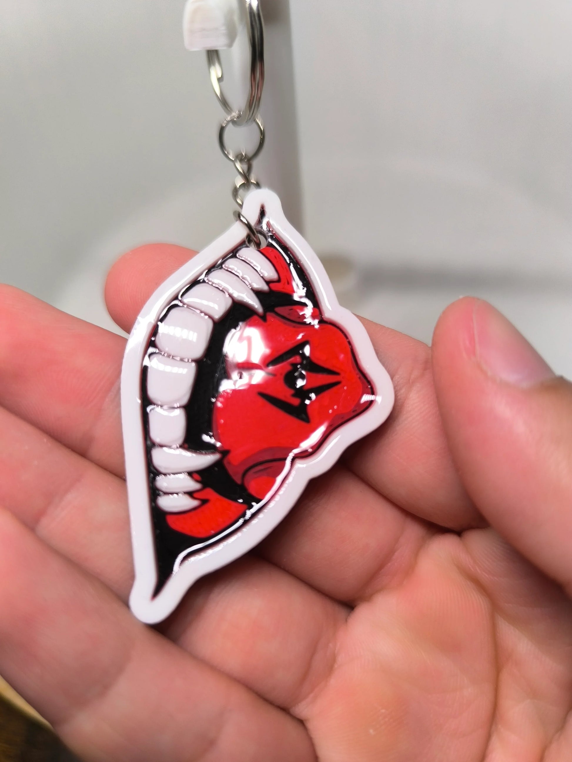 Porte-clés en main avec design de bouche rouge et blanche aux dents pointues, style cartoon effrayant