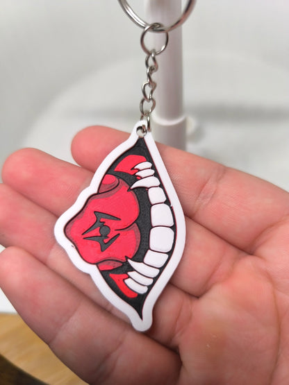 Porte-clés design bouche rouge stylisée avec dents blanches tenu en main