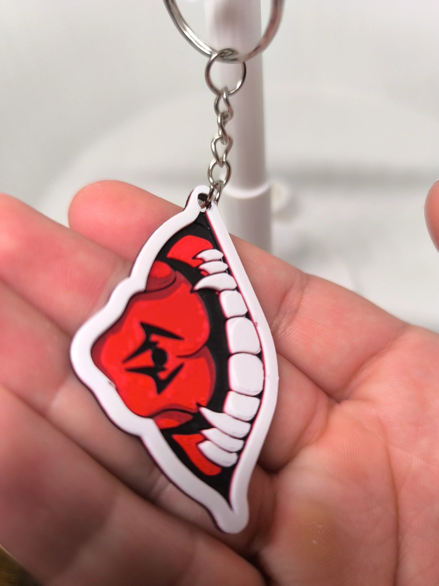 Porte-clés bouche rouge avec dents blanches pointues tenue dans la main