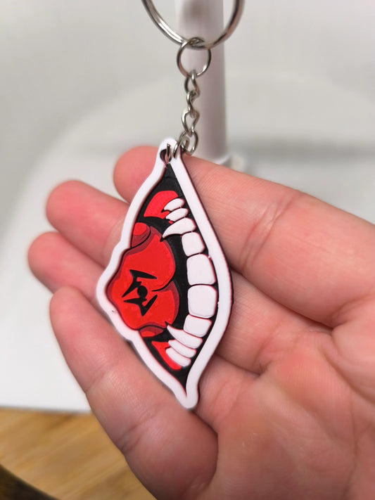 Porte-clés en main avec design bouche rouge et dents blanches sur fond noir