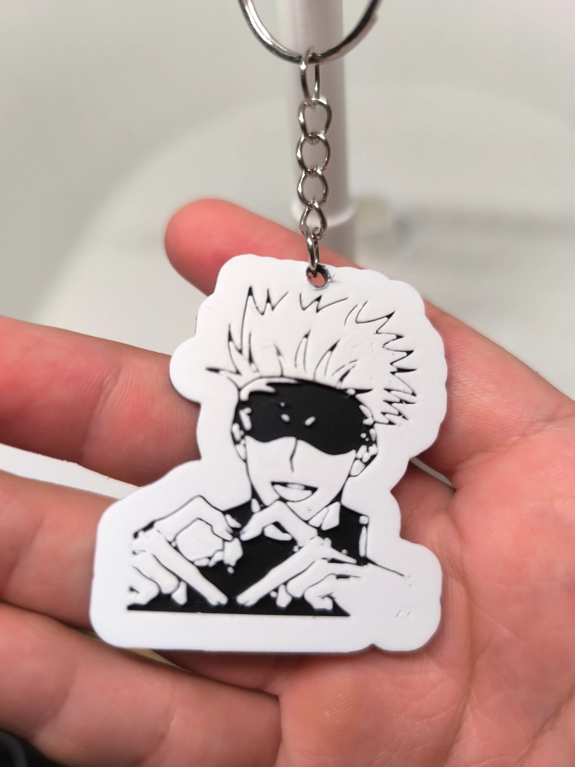 Porte-clés en plastique avec illustration noire et blanche d'un personnage manga aux cheveux ébouriffés et bandeau noir