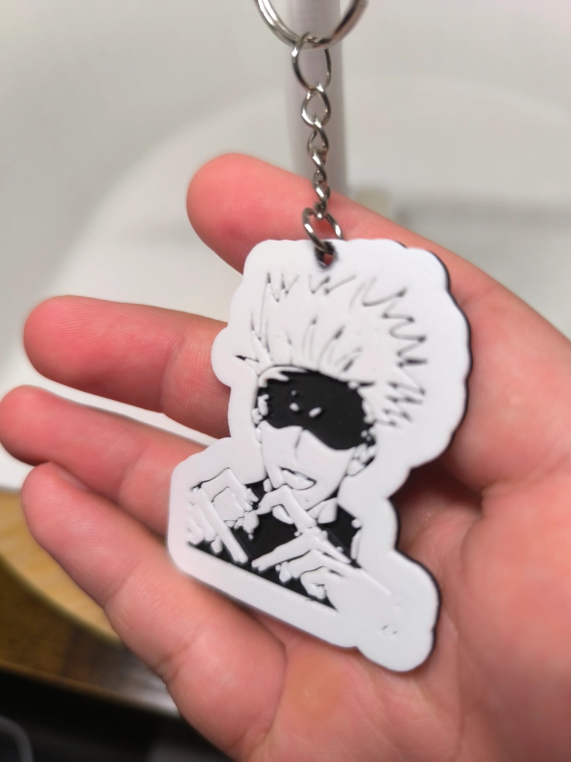 Porte-clé en plastique représentant un personnage de manga avec cheveux en piques et bandeau noir, tenu à la main