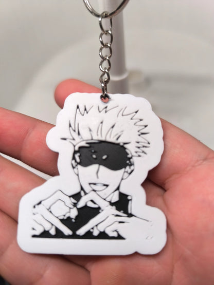 Porte-clés manga noir et blanc avec personnage souriant aux cheveux ébouriffés et bandeau noir