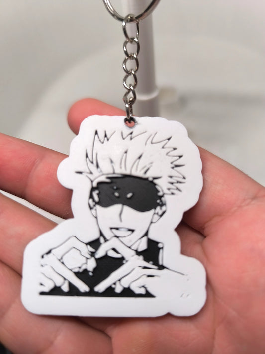 Porte-clés manga noir et blanc avec personnage souriant aux cheveux ébouriffés et bandeau noir