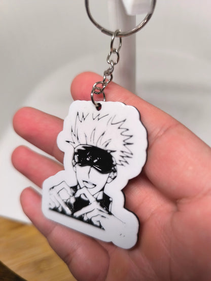 Porte-clés en plastique blanc avec illustration noire d'un personnage manga aux cheveux en pics et masque noir