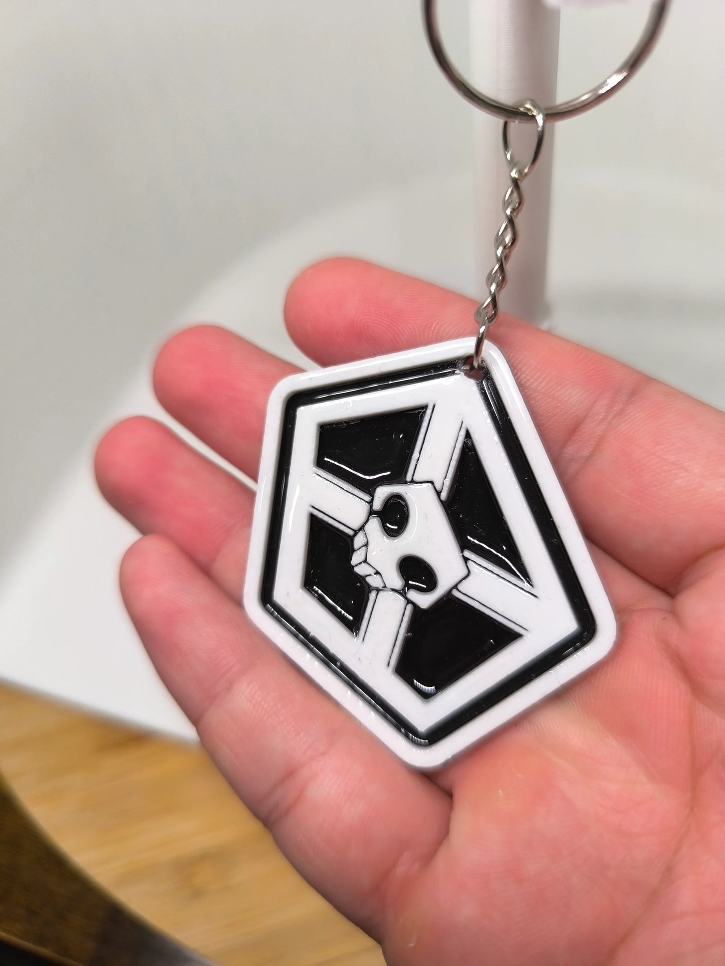 Porte-clés noir et blanc avec un motif de crâne dans un pentagone tenu dans une main