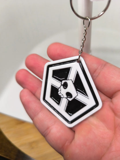 Porte-clés noir et blanc avec un motif de crâne dans un pentagone tenu dans une main