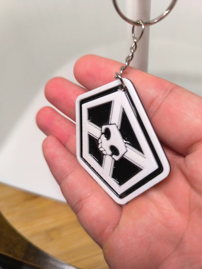 Porte-clés avec symbole blanc et noir tenu dans une main, fond flou