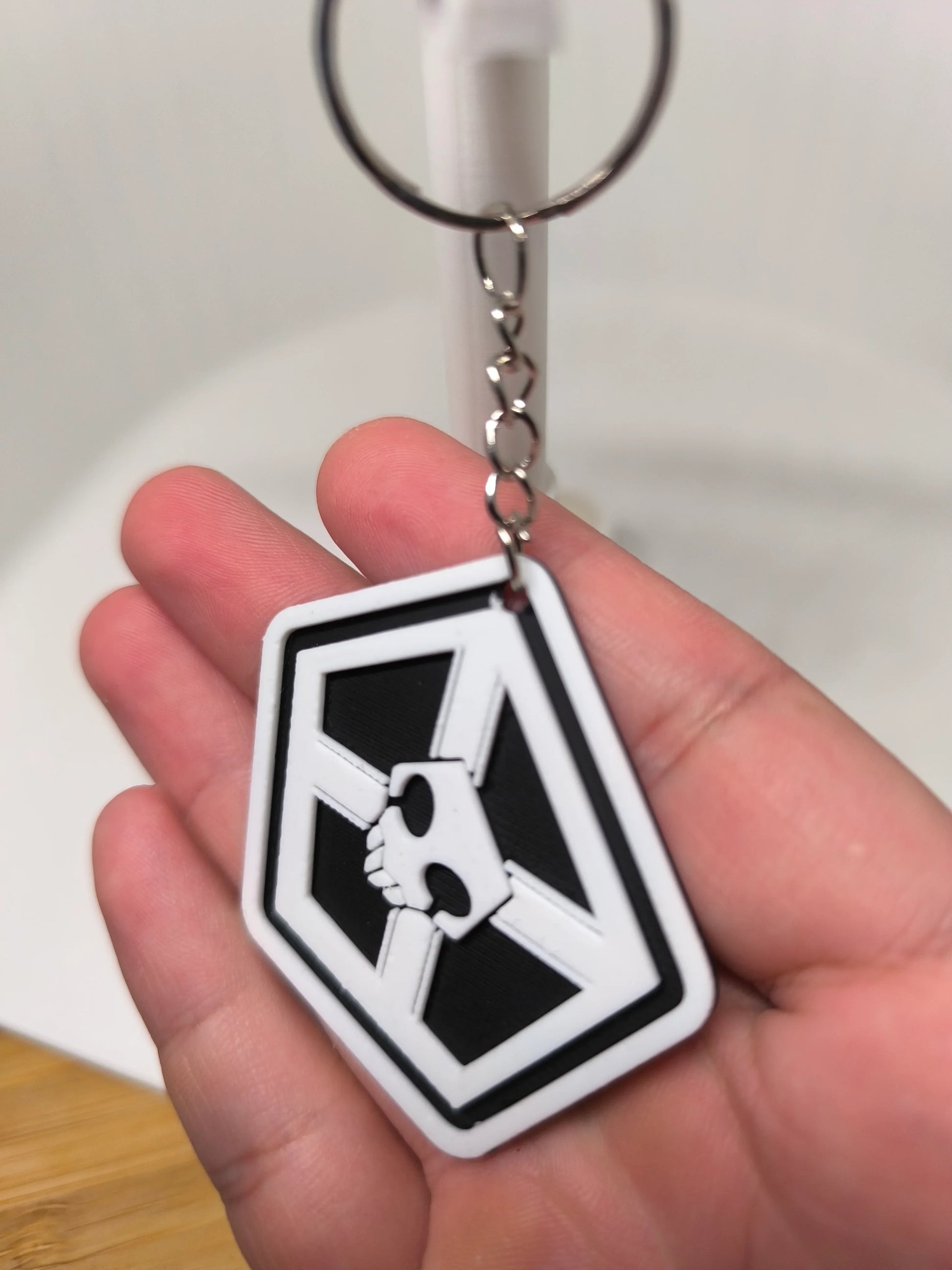 Porte-clés en plastique noir et blanc avec un crâne, tenu dans la main