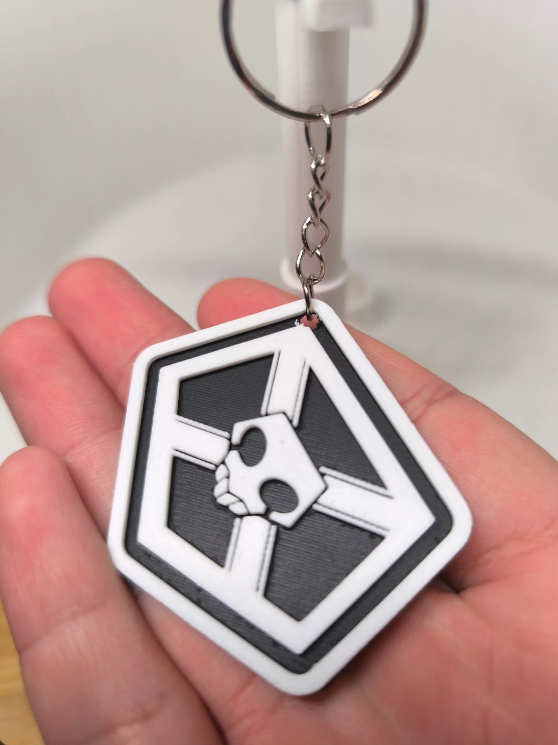 Porte-clés noir et blanc avec un motif tête de mort tenu dans la main