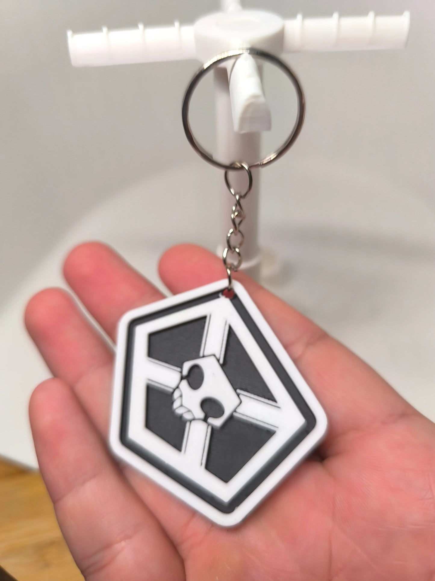 Porte-clés noir et blanc avec logo crâne géométrique tenu dans une main