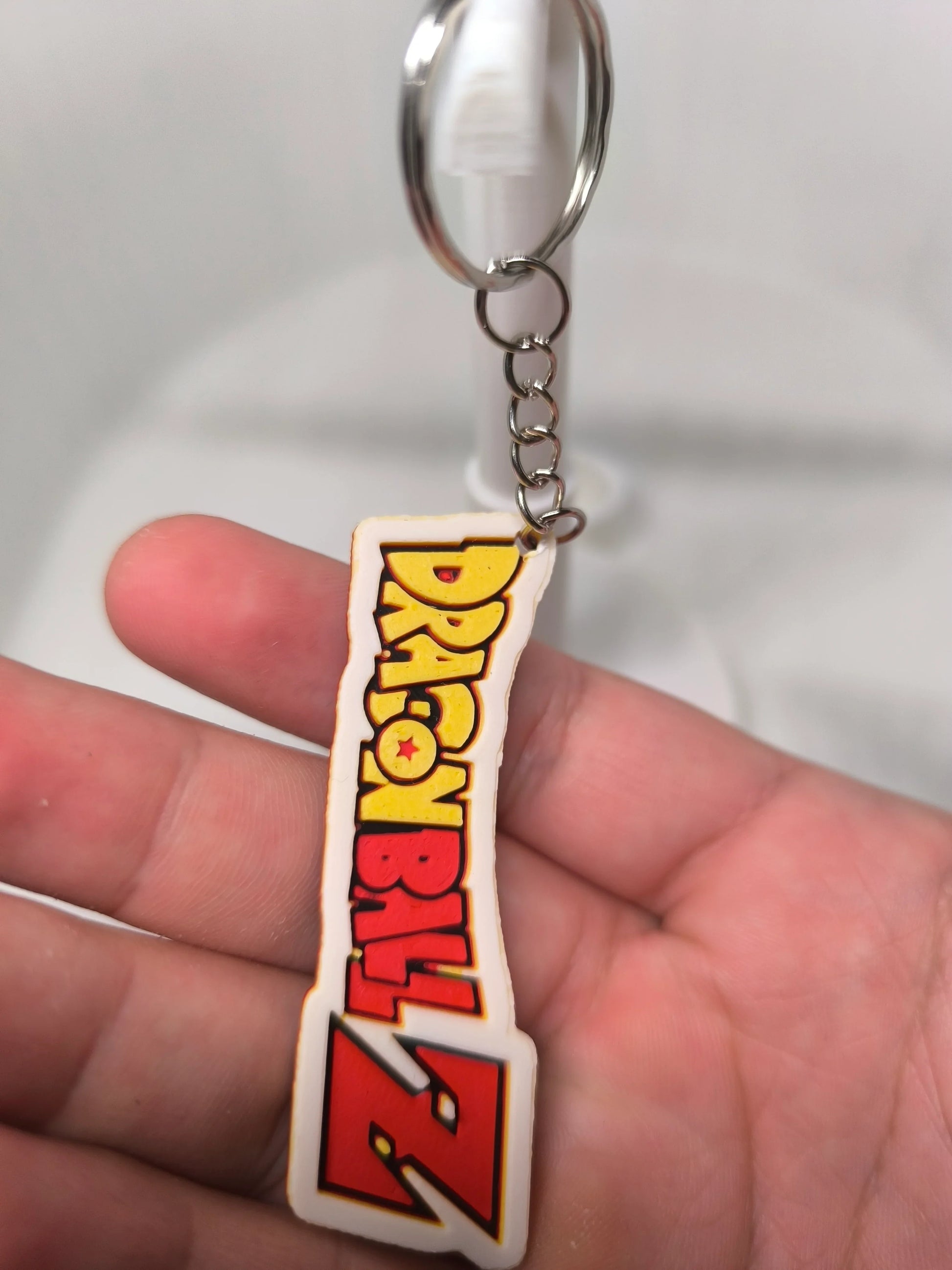 Porte-clés Dragon Ball Z tenu à la main sur fond blanc flou