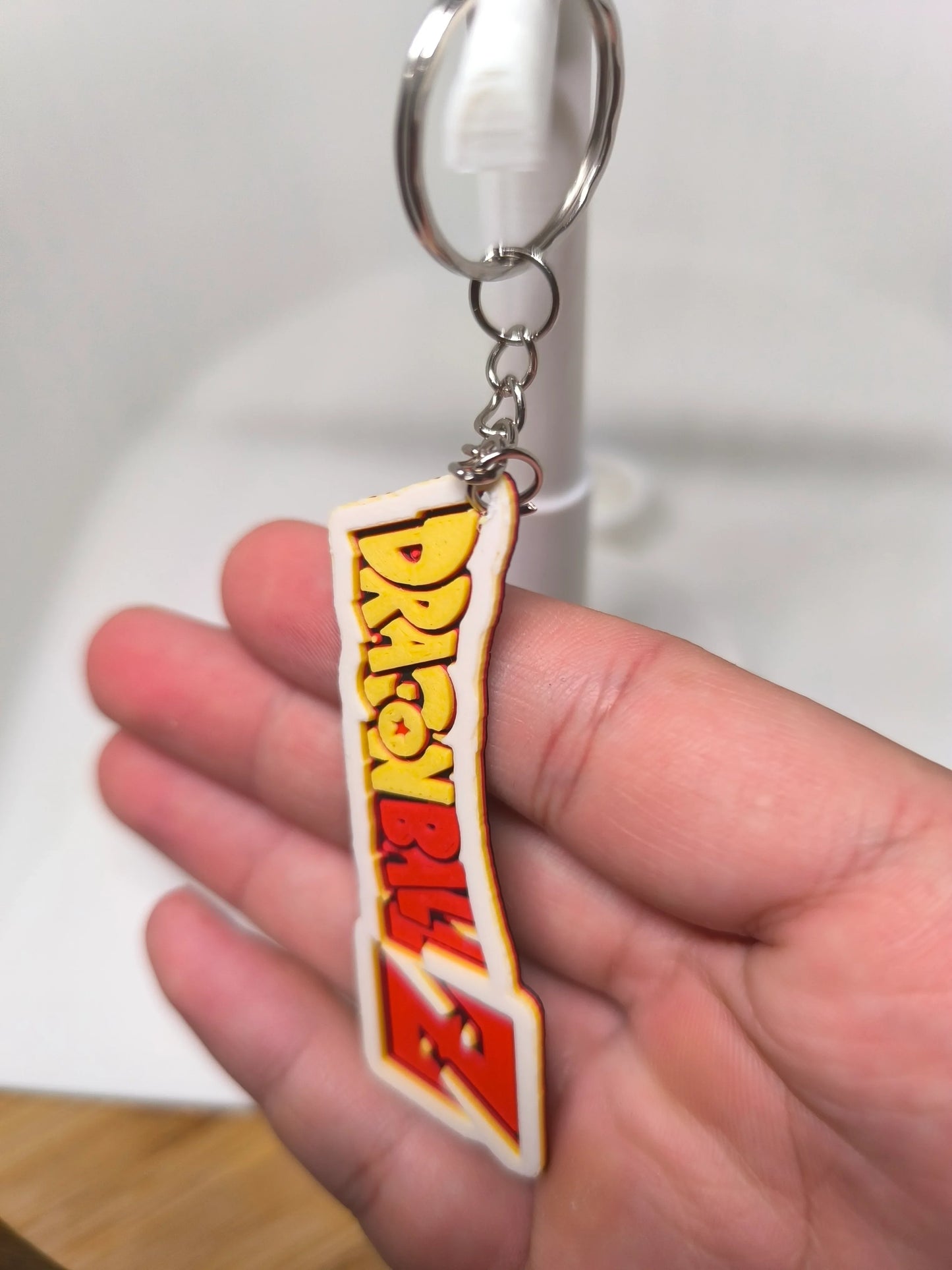 Porte-clés Dragon Ball Z tenu à la main avec logo coloré jaune et rouge