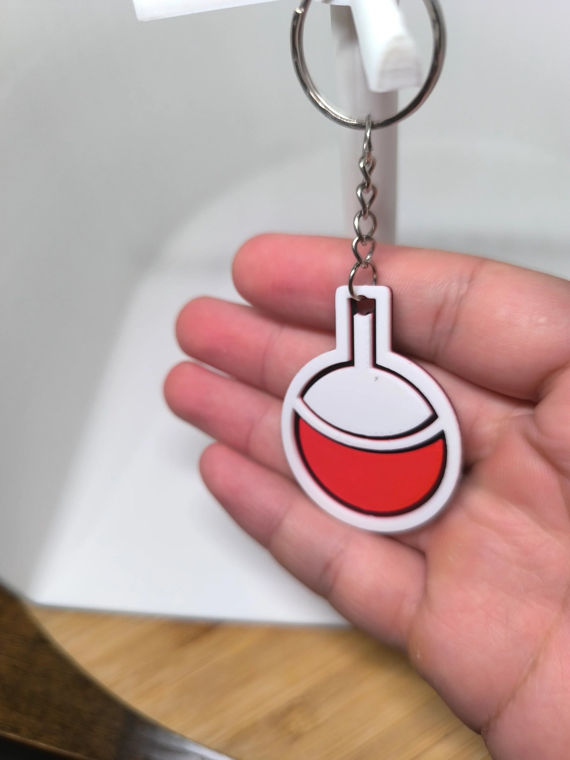 Porte-clés en forme de fiole à liquide rouge tenu dans une main