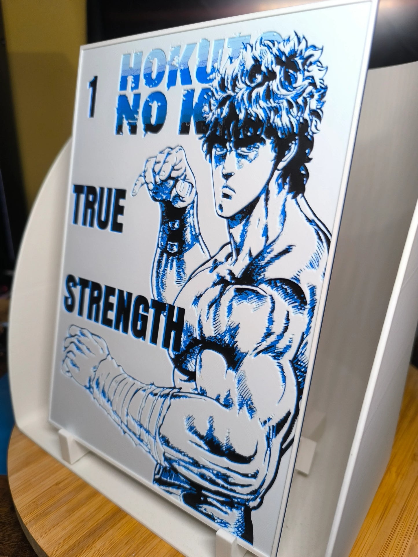 Illustration en bleu et noir de Kenshiro de Hokuto no Ken avec texte True Strength sur un panneau blanc