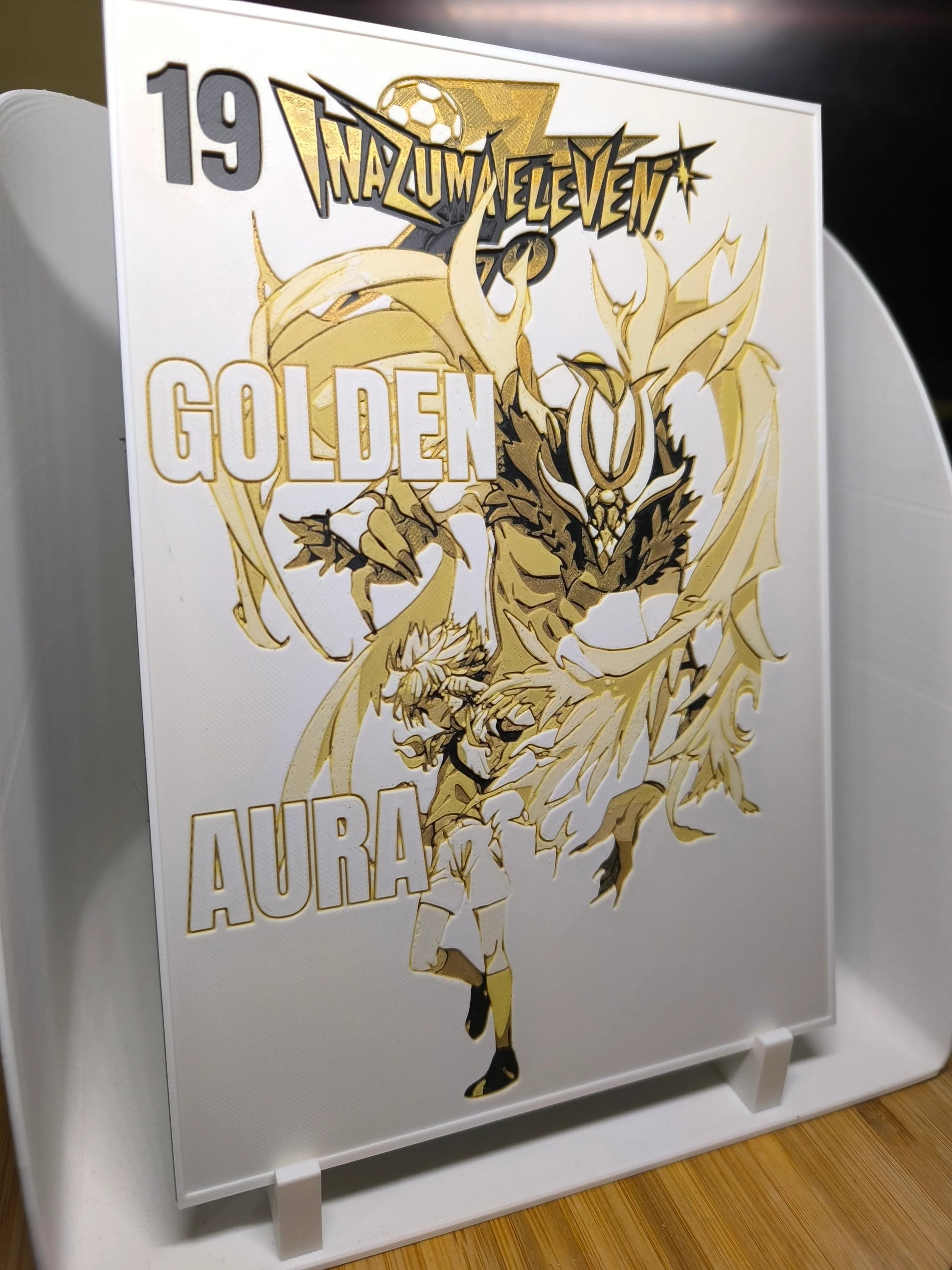 Illustration dorée Inazuma Eleven avec personnage en mouvement et texte Golden Aura sur fond blanc