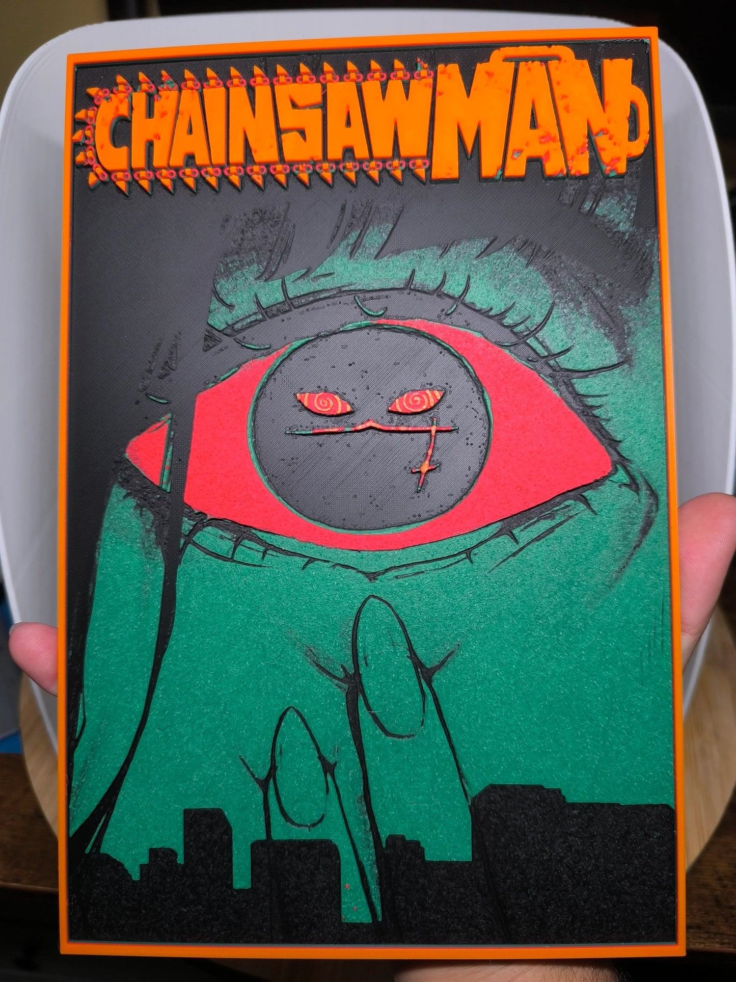 Couverture colorée de Chainsaw Man avec œil rouge vif et doigts verts sur fond noir et orange