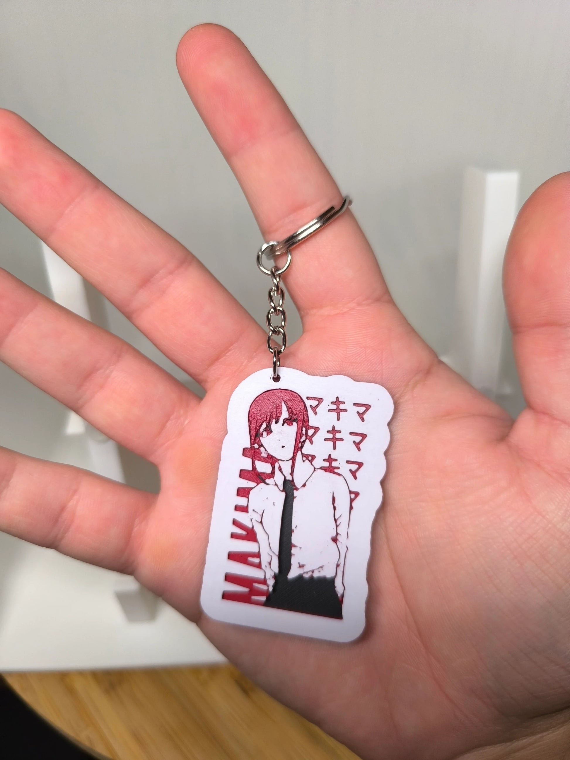 Porte-clés manga avec personnage féminin en chemise blanche et cravate noire tenu dans une main.