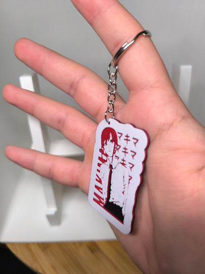 Porte-clés anime tenu par une main, personnage stylisé en blanc et rouge avec texte japonais
