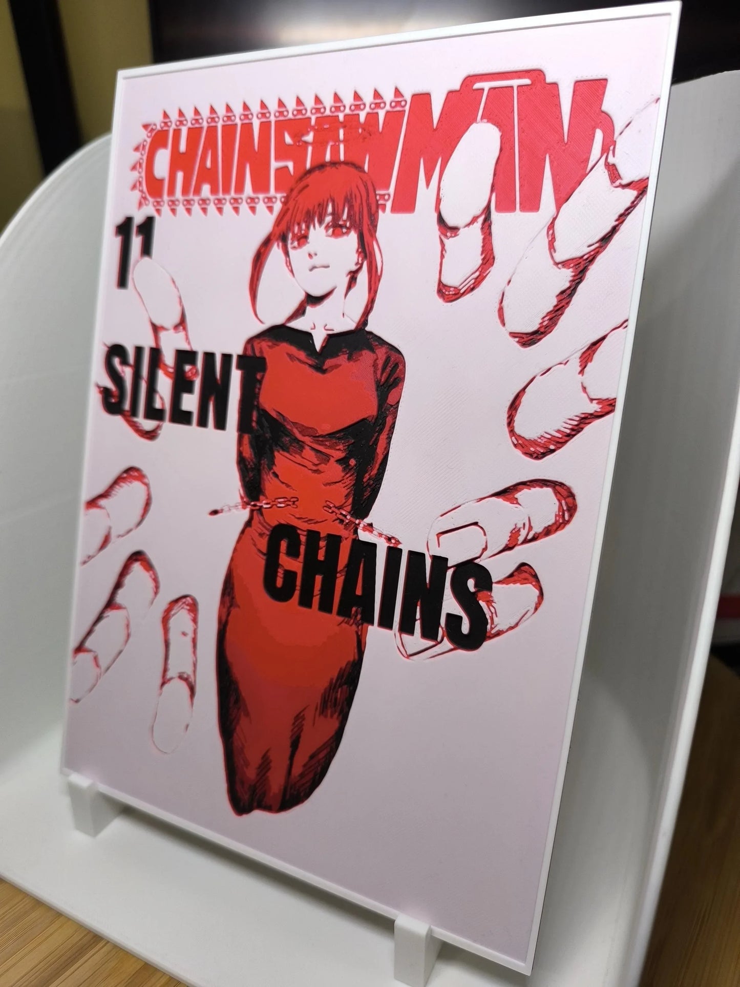 Couverture du manga Chainsaw Man volume 11 avec personnage féminin en robe rouge et menottes, thème chaînes silencieuses
