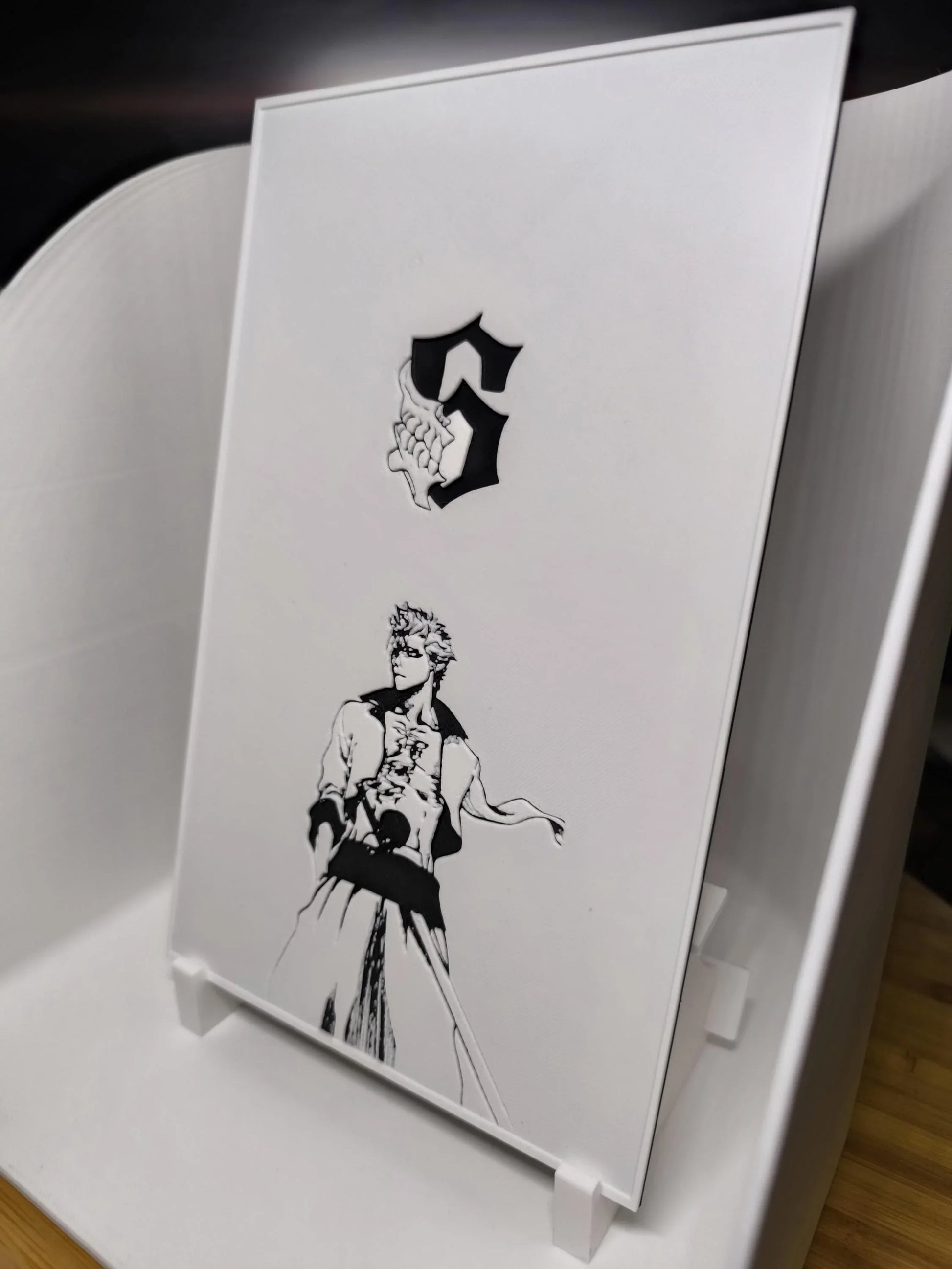 Figurine en noir et blanc d'un personnage d'anime avec épée, fond blanc minimaliste