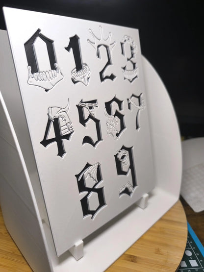 Chiffres gothiques noirs avec motifs squelettes en 3D sur plaque blanche dans boîte lumineuse