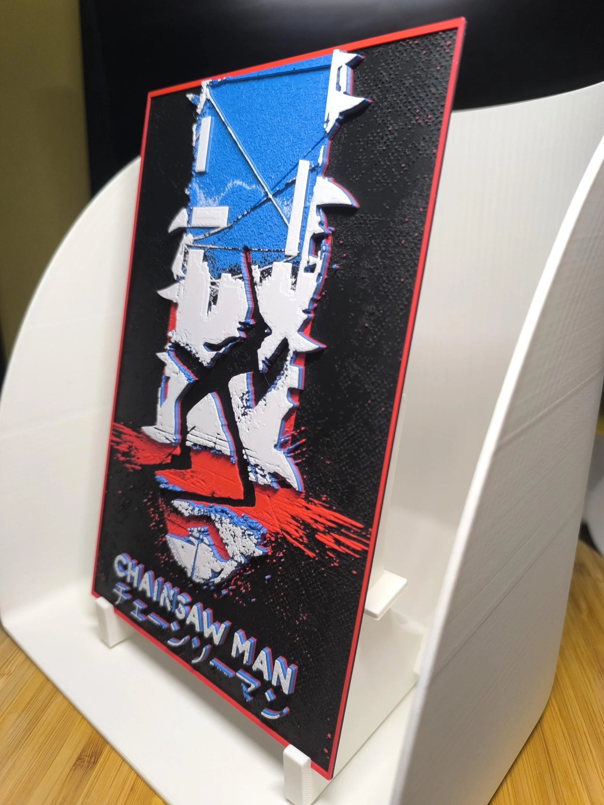Plaque décorative Chainsaw Man avec silhouette noire rouge et bleu sur fond noir texturé